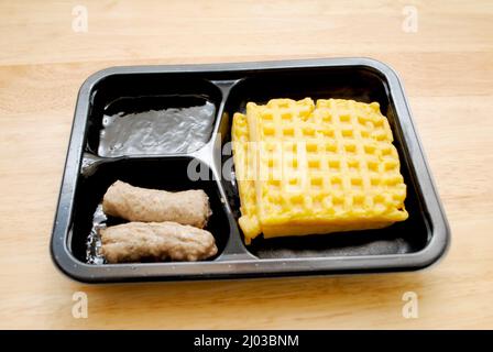 Mikrowellenfrühstück mit französischem Toast, Ahornsirup und Würstchen Stockfoto
