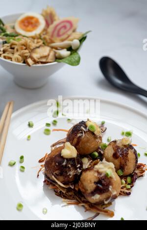 Eine Schüssel mit Ramen-Suppe und ein Teller Takoyaki-Snack Stockfoto