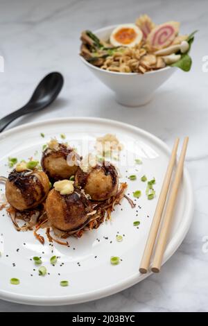 Eine Schüssel mit Ramen-Suppe und ein Teller Takoyaki-Snack Stockfoto