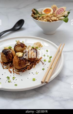 Eine Schüssel mit Ramen-Suppe und ein Teller Takoyaki-Snack Stockfoto