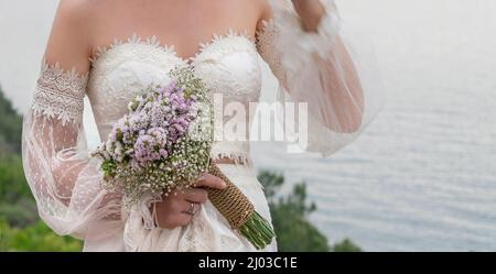 Braut Blume, Nahaufnahme Hand der Braut hält Blumenstrauß im Freien. Körperteil einer Frau trägt vintage Hochzeitskleid mit selektivem Fokus. Stockfoto
