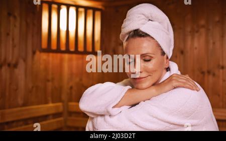 Sich in der Sauna wohlfühlen. Aufnahme einer reifen Frau in einer Sauna. Stockfoto