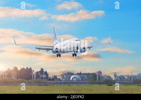 Passagierflugzeug, das vor dem Hintergrund eines wunderschönen Abendhimmels am Flughafen landet Stockfoto