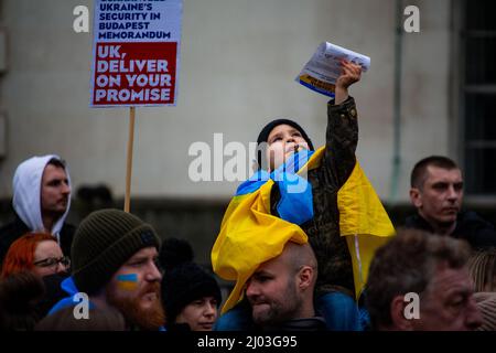 Ein kleiner Junge unter ukrainischer Flagge hält während proukrainischer Proteste am 2022. März einen Flyer vor der Downing Street hoch Stockfoto