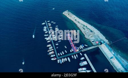 Luftaufnahme von oben nach unten von Bootsanlegestelle und Yachthafen in Budva, Montenegro. Weiße private Motorboote werden an der adriatischen Küste an der Anlegestelle vertäut. Yachtclub Stockfoto