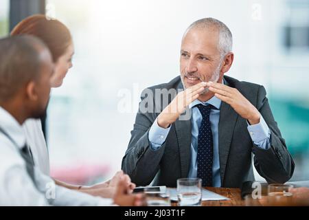 Überbrückung der Kluft zwischen Risiken und Chancen. Eine Aufnahme einer Gruppe von Geschäftsleuten, die in einem Büro eine Besprechung abhalten. Stockfoto