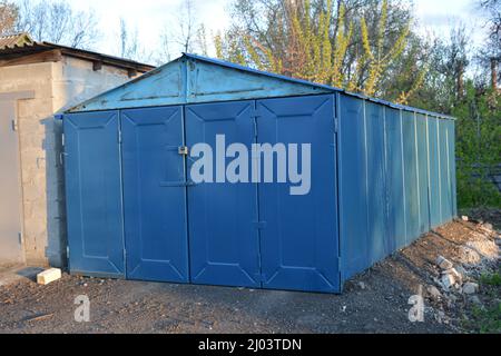 Blauer Plastikschuppen im Freien. Nahaufnahme. Alte Gebäude, Architektur, Parkplatz. Die blaue Metallgarage ist nicht weit vom Wohngebäude entfernt Stockfoto