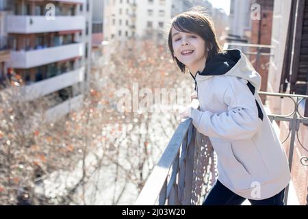 Kind, stehend auf einem Balkon in einer Wohnung in Barcelona, genießen Sonne und schönes Winterwetter, Spanien Stockfoto