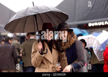 Am zweiten Tag des Cheltenham Festivals auf der Pferderennbahn von Cheltenham schützen sich Rennfahrer unter Regenschirmen vor dem Regen. Bilddatum: Mittwoch, 16. März 2022. Stockfoto