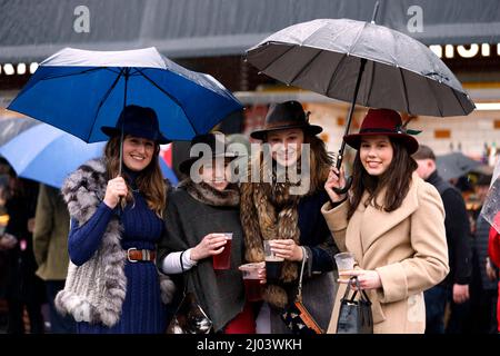 Am zweiten Tag des Cheltenham Festivals auf der Pferderennbahn von Cheltenham schützen sich Rennfahrer unter Regenschirmen vor dem Regen. Bilddatum: Mittwoch, 16. März 2022. Stockfoto