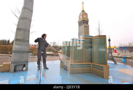 16. März 2022, Bayern, Günzburg: Sonja Hermann, Mitarbeiterin im Freizeitpark Legoland, befreit ein aus Legosteinen repliziertes Modell des Makkah Royal Clock Tower Hotels in Saudi-Arabien aus Sahara-Staub in Miniland. Rund zwei Wochen vor Saisonbeginn stellt der Staub die Parkmitarbeiter vor besondere Herausforderungen. Foto: Karl-Josef Hildenbrand/dpa Stockfoto