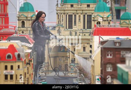 16. März 2022, Bayern, Günzburg: Sonja Hermann, Mitarbeiterin im Freizeitpark Legoland, befreit ein Modell der Stadt Berlin aus Legosteinen aus dem Sahara-Staub in Miniland. Etwa zwei Wochen vor Saisonbeginn stellt der Staub die Parkmitarbeiter vor besondere Herausforderungen. Foto: Karl-Josef Hildenbrand/dpa Stockfoto