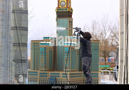 16. März 2022, Bayern, Günzburg: Sonja Hermann, Mitarbeiterin im Freizeitpark Legoland, befreit ein aus Legosteinen repliziertes Modell des Makkah Royal Clock Tower Hotels in Saudi-Arabien aus Sahara-Staub in Miniland. Rund zwei Wochen vor Saisonbeginn stellt der Staub die Parkmitarbeiter vor besondere Herausforderungen. Foto: Karl-Josef Hildenbrand/dpa Stockfoto