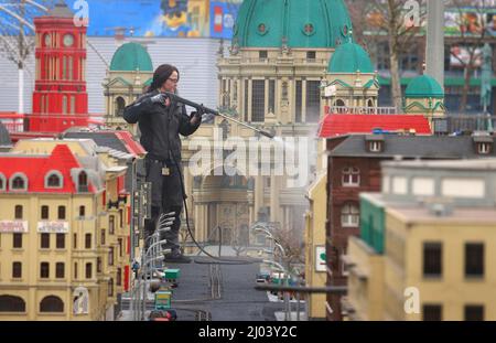 16. März 2022, Bayern, Günzburg: Sonja Hermann, Mitarbeiterin im Freizeitpark Legoland, befreit ein Modell der Stadt Berlin aus Legosteinen aus dem Sahara-Staub in Miniland. Etwa zwei Wochen vor Saisonbeginn stellt der Staub die Parkmitarbeiter vor besondere Herausforderungen. Foto: Karl-Josef Hildenbrand/dpa Stockfoto