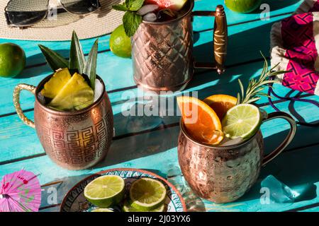 Erfrischende Mocktails garniert mit verschiedenen Früchten und Kräutern, in hellem Sonnenlicht. Stockfoto