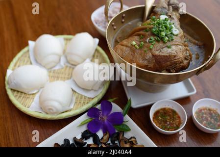 Geschmortes Schweineknöchel mit Soße-Suppe im chinesischen Yunnan-Stil oder in Soße geschmortes Yunnan-Schweinekeul mit Mantou, chinesischem Essen. Stockfoto