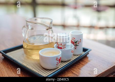 Tee im Glas mit Teekannen auf dem Holztisch, chinesische und japanische Kulturen. Stockfoto