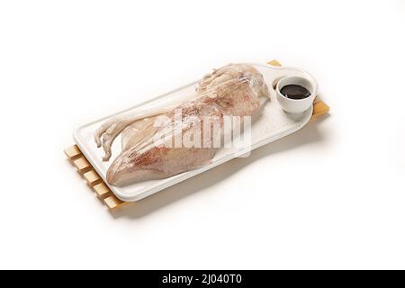 High-Angle-Aufnahme eines frischen Tintenfischs auf einer Platte, die auf weißem Hintergrund isoliert ist Stockfoto