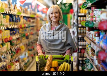Porträt einer ziemlich älteren Dame, die im Supermarkt einkaufen geht Stockfoto