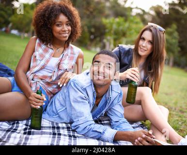 Toller Tag für ein Picknick im Park. Porträt einer Gruppe von glücklichen jungen Freunden, die während eines Picknicks einen Drink zu sich nehmen. Stockfoto