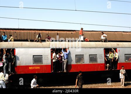 Indische Pendler reisen auf dem Dach eines Zuges, der Stunts in Nahverkehrszügen durchführt; 6 Milliarden Pendler reisen in Nahverkehrszügen des westlichen Vororts Mumbai. Stockfoto