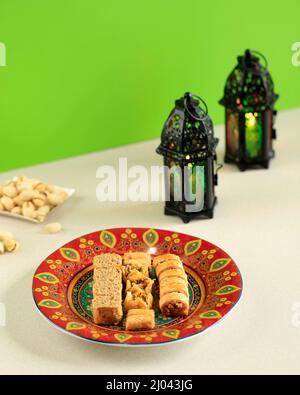 Traditionelle türkische, arabische, mittelöstliche Baklava. Draufsicht. Arabisch gebackene Süßigkeiten auf weißem Teller auf dunklem Holztisch. Mini Baklawa. Ramadan Eid Konz Stockfoto