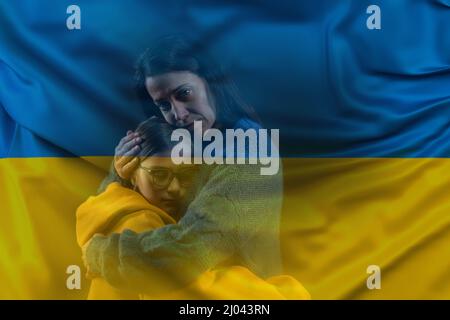 Die traurige Mutter umarmte ihre Tochter und die ukrainische Flagge Stockfoto