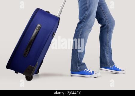 Junger Mann, der mit einer in Weiß isolierten Reisetasche läuft Stockfoto