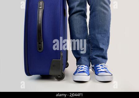 Junger Mann wartet mit Reisetasche isoliert in weiß Stockfoto