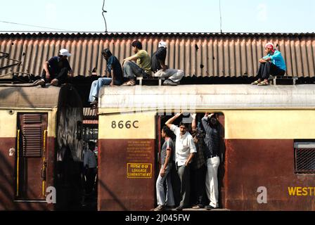 Indische Pendler reisen auf dem Dach eines Zuges, der Stunts in Nahverkehrszügen durchführt; 6 Milliarden Pendler reisen in Nahverkehrszügen des westlichen Vororts Mumbai. Stockfoto