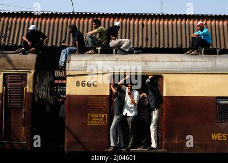 Indische Pendler reisen auf dem Dach eines Zuges, der Stunts in Nahverkehrszügen durchführt; 6 Milliarden Pendler reisen in Nahverkehrszügen des westlichen Vororts Mumbai. Stockfoto