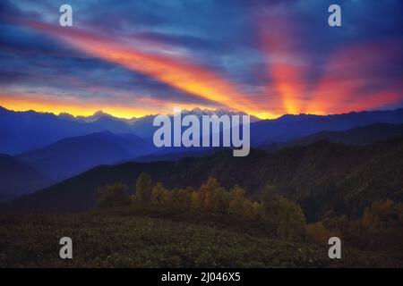 Fantastische rote Sonnenstrahlen mit bewölktem Himmel am Fuße des Mt. Ushba. Dramatische Morgenszene. Obersvaneti, Mestia, Georgien, Europa. Hoher Kaukasuskamm Stockfoto