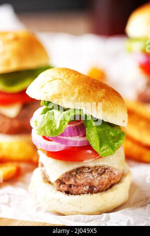 Mini-Hamburger mit Tomaten, Salat und Käse auf Holzbrett Stockfoto