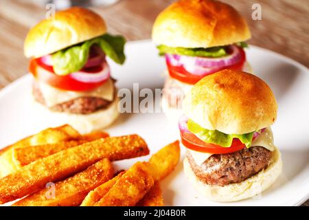 Mini-Hamburger mit Tomaten, Salat und Käse auf Holzbrett Stockfoto