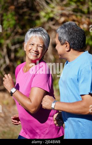 Sich gegenseitig motivieren, gesund zu bleiben. Aufnahme eines reifen Paares, das an einem sonnigen Tag zusammen joggt. Stockfoto