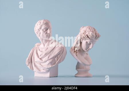 Zwei kleine weiße Büsten im antiken Stil aus Rom oder Griechenland, die Männer auf blauem Hintergrund darstellen Stockfoto