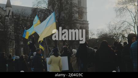 London, Großbritannien - 03 06 2022: Eine Menschenmenge bei einem Protest auf dem Parliament Square, mit blauen und gelben ukrainischen Fahnen, die im Wind wehen. Stockfoto