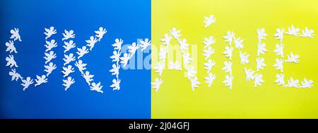 Wort Ukraine aus Papier Engel auf einem gelb-blauen Hintergrund, die Farben der Nationalflagge gelegt. Stehe mit der Ukraine Stockfoto