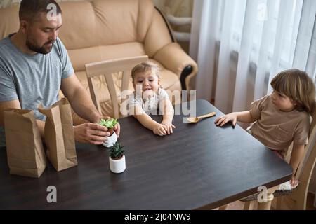 Papa und zwei Kinder sind dabei, Sukkulenten in neue Töpfe zu bringen Stockfoto