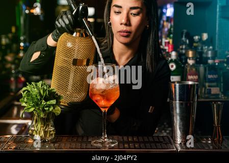 Die lateinamerikanische Brünette Kellnerin bereitet an der Bar einen Cocktail zu Stockfoto