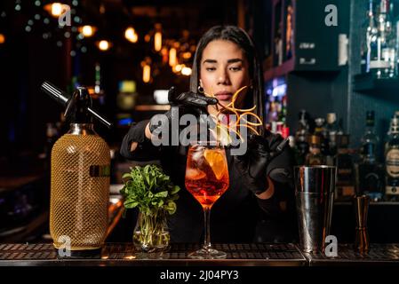 Die lateinamerikanische Brünette Kellnerin bereitet an der Bar einen Cocktail zu Stockfoto