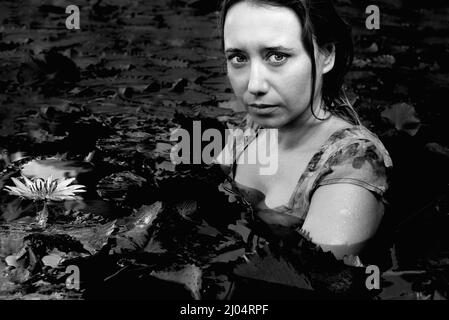 Verängstigtes Mädchen, das mit Lotos im See sitzt Stockfoto