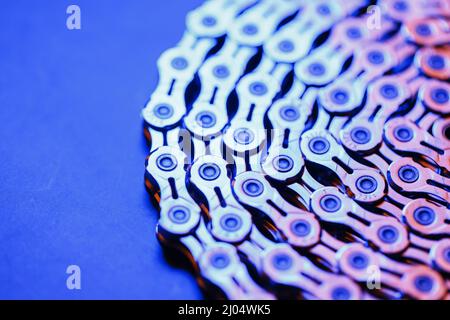 Muster einer technologischen Fahrradkette, umflochten in einen Kreis mit blau-violetter Beleuchtung Stockfoto