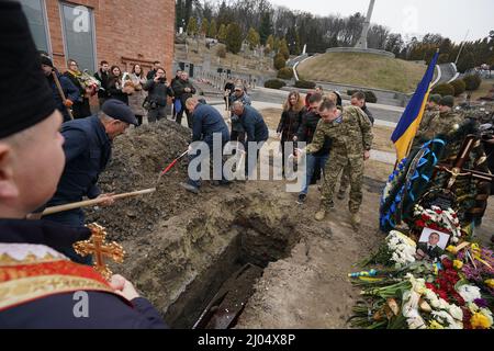 Lviv, Ukraine. 16. März 2022. Beerdigung des ukrainischen Militärleutnants Eduard Pertowitsch Nezehlec, der am 16. März 2022 auf dem Friedhof in Lytschakiv in der westukrainischen Stadt Lemberg während der russischen Invasion in der Ukraine getötet wurde. Etwa 30 Raketen wurden teilweise von der ukrainischen Verteidigung abgefangen, aber 9 von ihnen trafen auf den Stützpunkt Javoriv, etwa 20 km von der polnischen Grenze entfernt, der im Februar NATO-Truppen erhielt. 35 Soldaten starben bei dem Angriff, 135 wurden verletzt. (Bild: © Bryan Smith/ZUMA Press Wire) Stockfoto