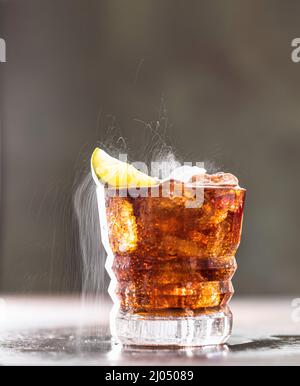 Cuba Libre mit braunem Rum, Cola, Minze und Limette. Kaltes Longdrink, alkoholischer Cocktail. Platz für Text, dunkler Hintergrund. Stockfoto