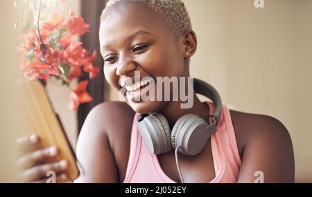 Meine sozialen Medien werden aktualisiert. Eine kurze Aufnahme einer attraktiven jungen Frau, die alleine sitzt und ihr Handy nach einer Yoga-Sitzung in der Halle benutzt. Stockfoto