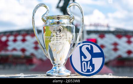 14. Juni 2021, Gelsenkirchen, Deutschland. Das Emblem des Fußballvereins FC Schalke 04 und des UEFA Champions League Cups vor dem Hintergrund eines Moders Stockfoto