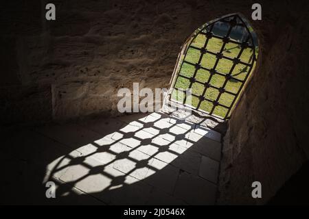 Verschlossenes Fenster im dunklen, alten Gefängnisinneren, abstrakter, dunkler architektonischer Hintergrund Stockfoto