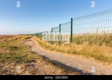 West Kirby, Großbritannien: Küstenpfad an der Metallgrenze des Golfplatzes Royal Liverpool (Hoylake) auf der Halbinsel Wirral. Stockfoto