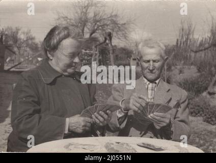 Original Vintage-Foto über ältere alte Paare, die um eine Spielkarte (in deutscher Sprache) aus den 1940er Jahren sitzen, um im Sommer Vintage-Kartenspieler Stockfoto